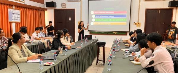 Dr PHAN Thi Ngan, du Cirad, se tient au fond de la salle et parle au micro, une diapositive étant projetée derrière elle. Les participants sont assis de part et d'autre d'une longue table de conférence.