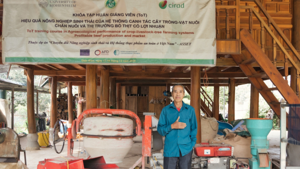 Mr. Vi Van Bun, a farmer from Dien Bien province, stands in front of his house where equipment used for crop–livestock integration training under the ASSET project is displayed.