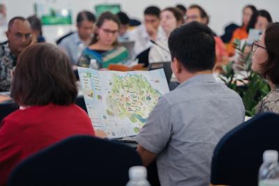 Participants at the ASSET Final Workshop review a map showcasing territorial branding initiatives in Moc Chau district, Vietnam.